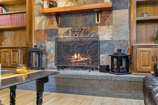 living area with a brick fireplace and wood finished floors