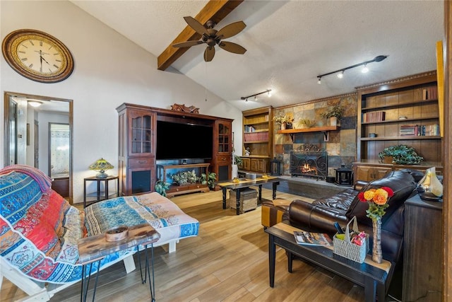 living area with ceiling fan, lofted ceiling with beams, light wood finished floors, and a textured ceiling