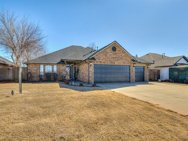 single story home with a front yard, fence, an attached garage, concrete driveway, and brick siding