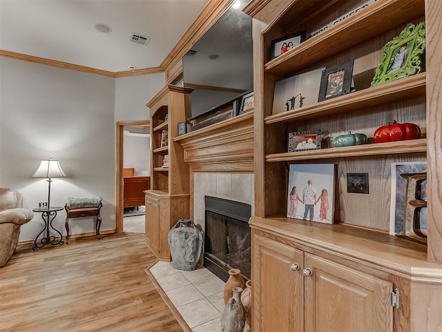 living area featuring visible vents, light wood-style flooring, a fireplace, crown molding, and baseboards