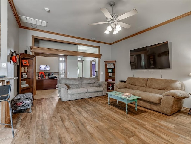 living area featuring visible vents, ornamental molding, a ceiling fan, and light wood finished floors