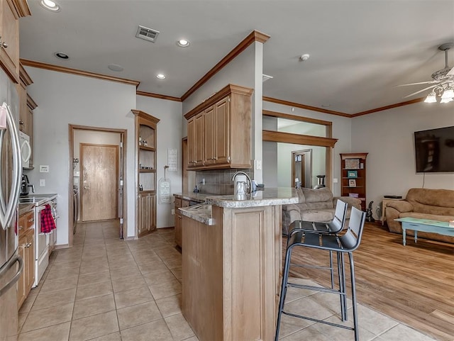 kitchen featuring visible vents, open floor plan, stainless steel electric stove, a peninsula, and a kitchen breakfast bar