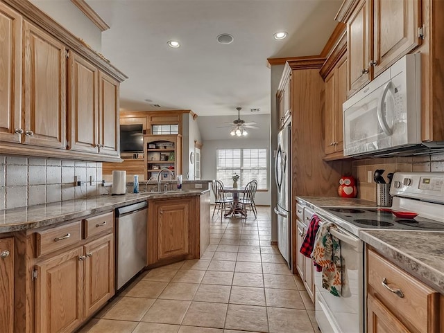 kitchen with a sink, stainless steel appliances, backsplash, and ceiling fan