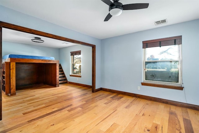 interior space with ceiling fan, light wood-style floors, visible vents, and baseboards