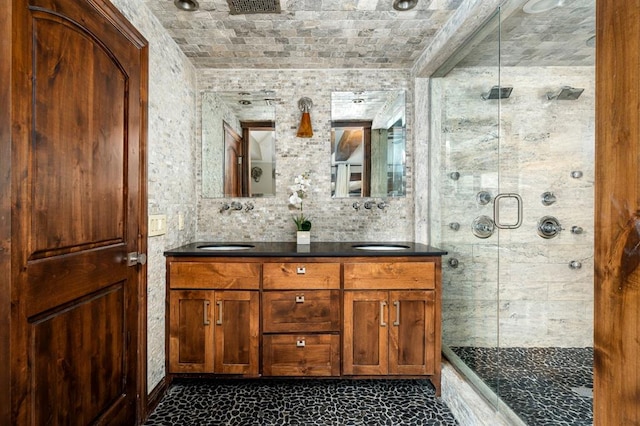 bathroom featuring double vanity, a stall shower, and a sink