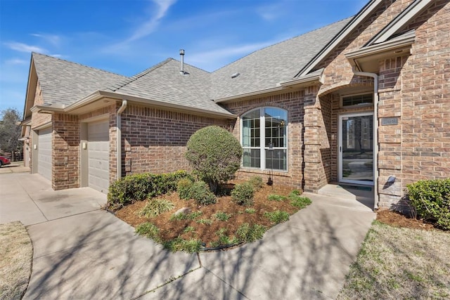 exterior space featuring an attached garage, brick siding, driveway, and a shingled roof