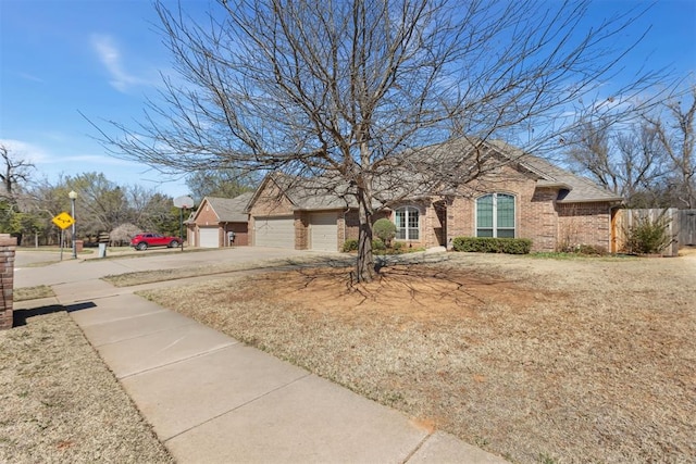 view of front facade with brick siding, an attached garage, a shingled roof, fence, and driveway