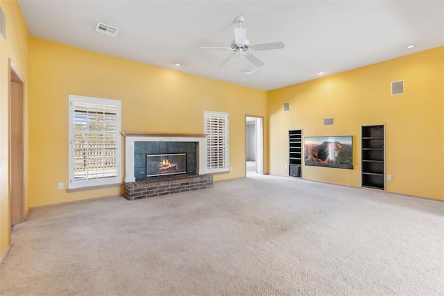 unfurnished living room with a tiled fireplace, carpet flooring, a ceiling fan, and visible vents