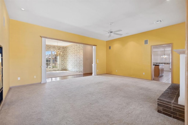 spare room featuring carpet flooring, ceiling fan with notable chandelier, baseboards, and visible vents