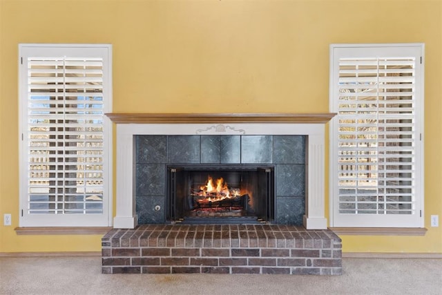 room details featuring a lit fireplace, baseboards, and carpet