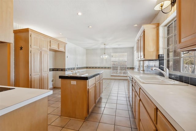 kitchen with light tile patterned floors, light brown cabinets, a center island with sink, and a sink