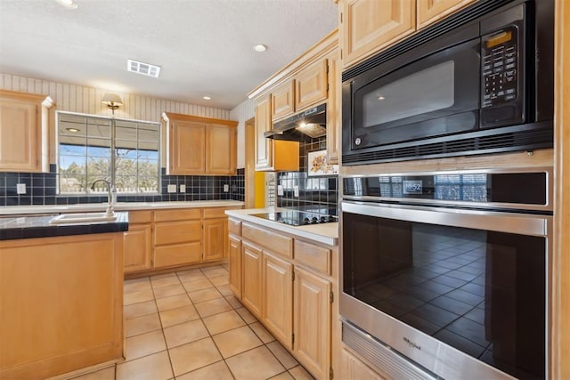 kitchen with black appliances, visible vents, under cabinet range hood, and light brown cabinetry