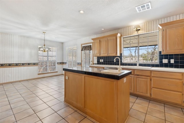 kitchen with visible vents, light brown cabinets, a kitchen island, an inviting chandelier, and light tile patterned floors