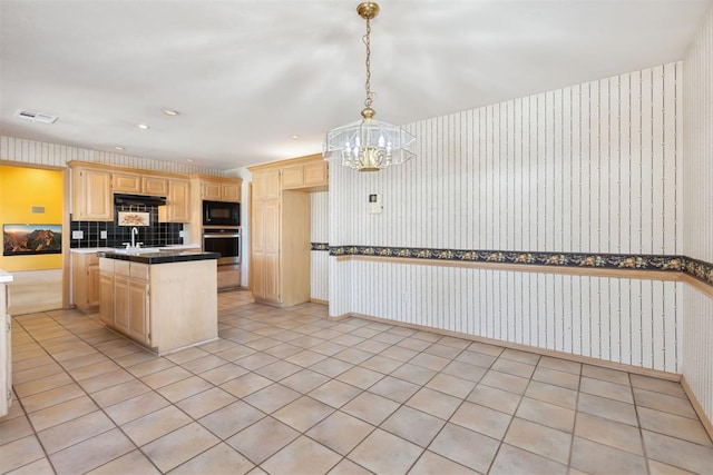 kitchen with wallpapered walls, black microwave, light brown cabinetry, stainless steel oven, and an inviting chandelier