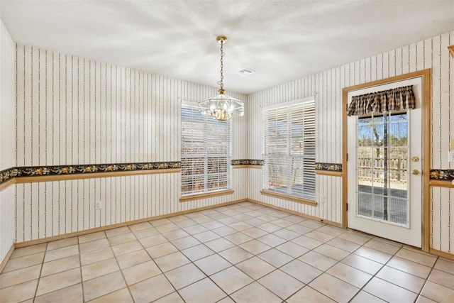 unfurnished dining area featuring tile patterned floors, baseboards, an inviting chandelier, and wallpapered walls