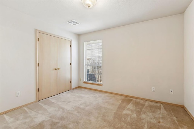 unfurnished bedroom with visible vents, baseboards, a closet, and carpet flooring