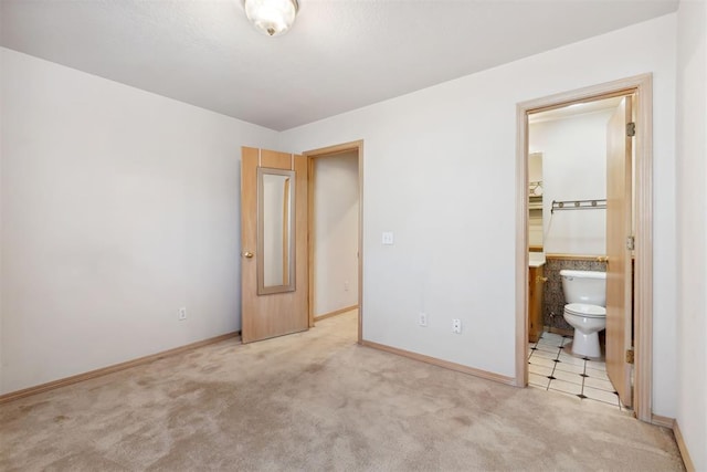 unfurnished bedroom with baseboards, carpet, and ensuite bathroom