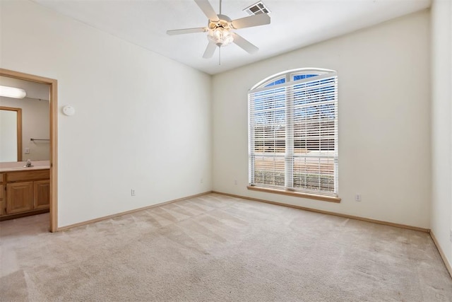 unfurnished room with visible vents, baseboards, ceiling fan, light carpet, and a sink