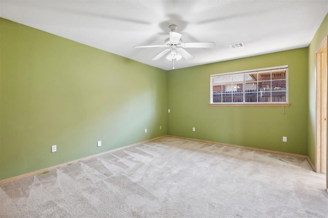 carpeted spare room featuring visible vents and ceiling fan