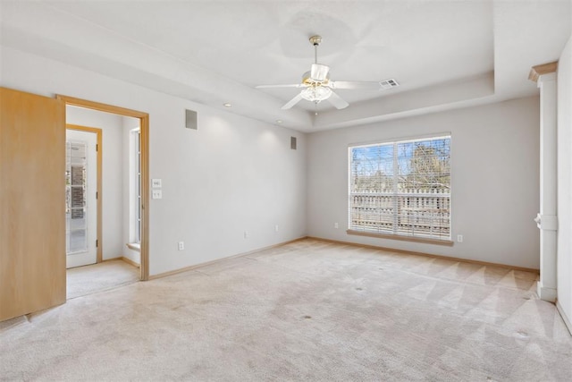 spare room with visible vents, ceiling fan, a tray ceiling, and carpet floors