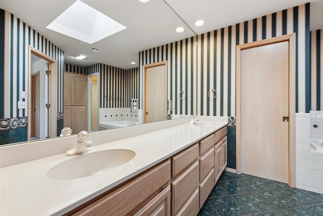 bathroom featuring a sink, a skylight, and wallpapered walls