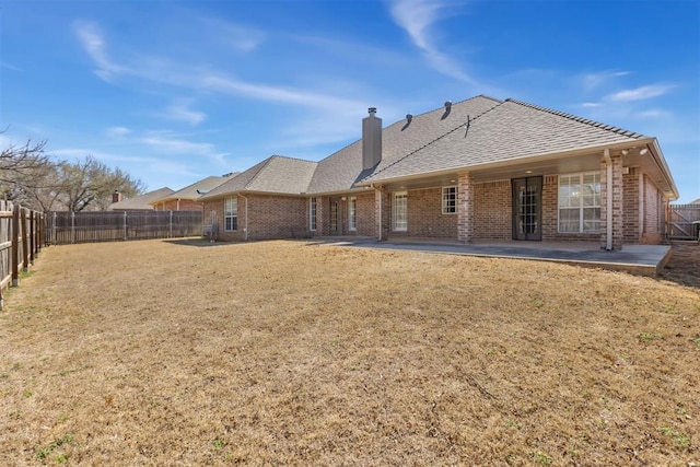 rear view of property featuring a patio area, brick siding, a fenced backyard, and a lawn