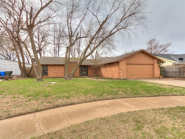 view of front facade with fence, concrete driveway, a front yard, a garage, and brick siding