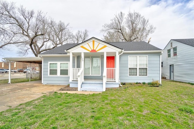 view of front facade featuring a carport, concrete driveway, a front lawn, and roof with shingles