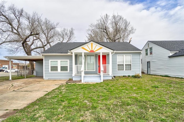 view of front of home featuring an attached carport, concrete driveway, a front yard, and roof with shingles