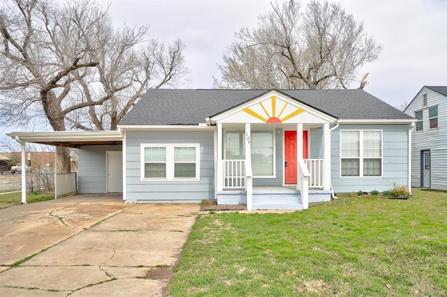 view of front of home featuring an attached carport, concrete driveway, a front yard, roof with shingles, and covered porch