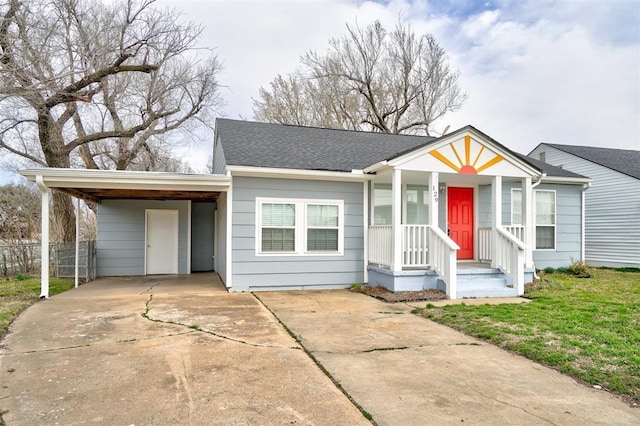 view of front of home with a shingled roof, an attached carport, concrete driveway, and fence