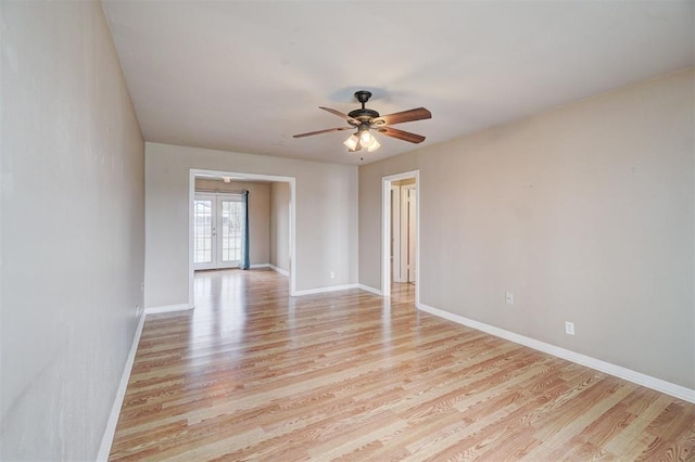 empty room with ceiling fan, french doors, light wood-type flooring, and baseboards