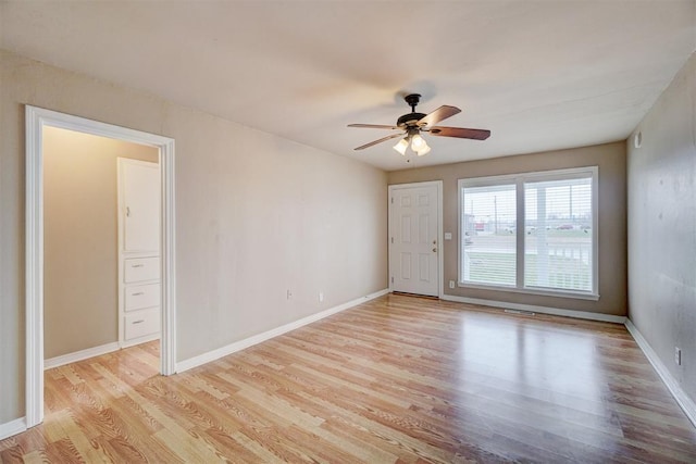 spare room with light wood-type flooring, baseboards, visible vents, and ceiling fan