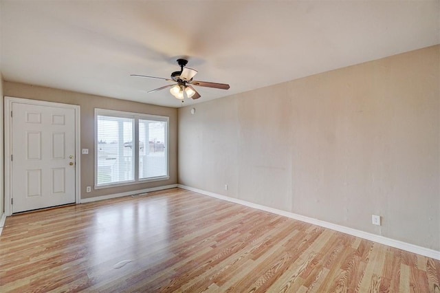 empty room with baseboards, ceiling fan, and light wood finished floors