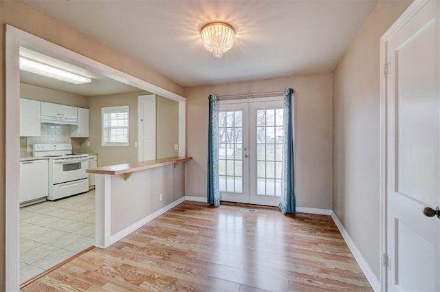 kitchen featuring backsplash, a peninsula, french doors, white cabinets, and white appliances