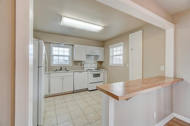 kitchen with a healthy amount of sunlight, white appliances, a peninsula, and a sink