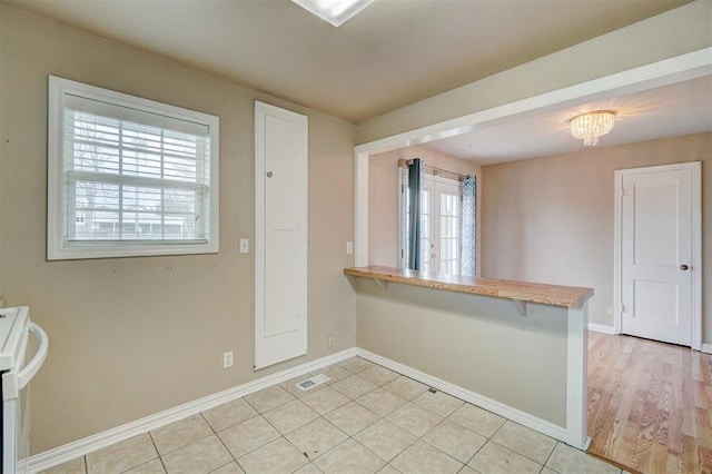 kitchen with stove, light tile patterned floors, baseboards, and visible vents