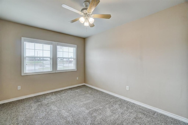 carpeted spare room with a ceiling fan and baseboards