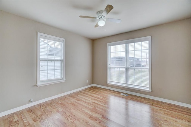 spare room with visible vents, a ceiling fan, baseboards, and wood finished floors