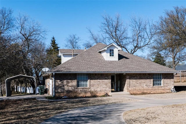 view of front of house featuring a carport, brick siding, driveway, and a shingled roof