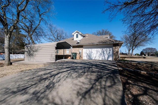 exterior space with a carport, concrete driveway, brick siding, and roof with shingles