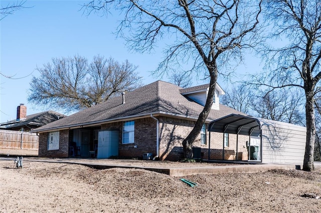 view of side of property featuring a carport, fence, and brick siding