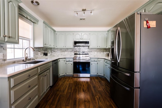 kitchen featuring visible vents, a sink, dark wood-style floors, appliances with stainless steel finishes, and light countertops