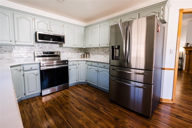 kitchen featuring dark wood finished floors, backsplash, stainless steel appliances, and light countertops