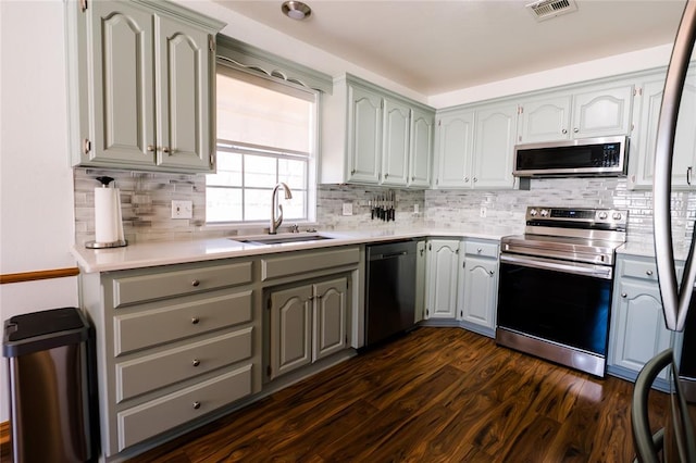 kitchen featuring visible vents, dark wood-type flooring, a sink, appliances with stainless steel finishes, and light countertops