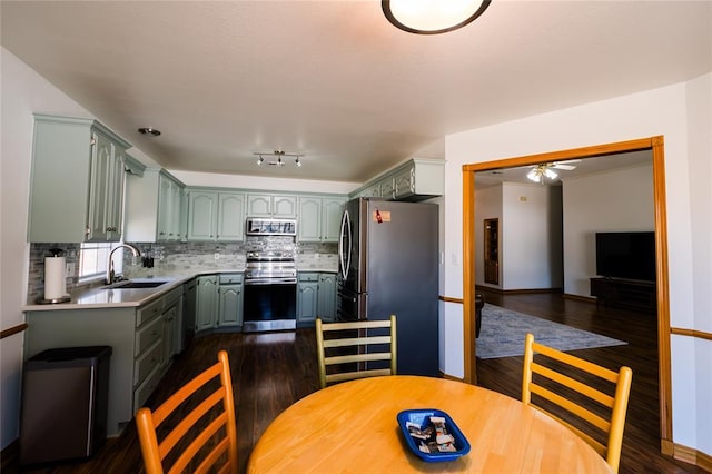 kitchen with tasteful backsplash, a sink, light countertops, stainless steel appliances, and dark wood-style flooring