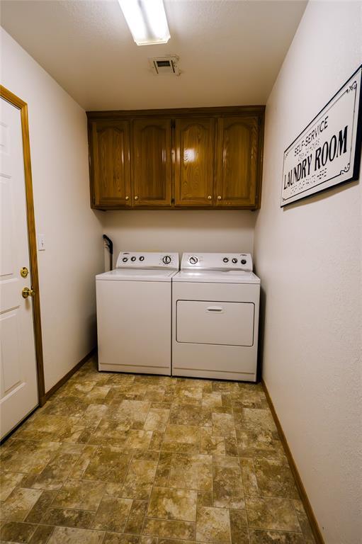 laundry room featuring visible vents, independent washer and dryer, stone finish floor, cabinet space, and baseboards