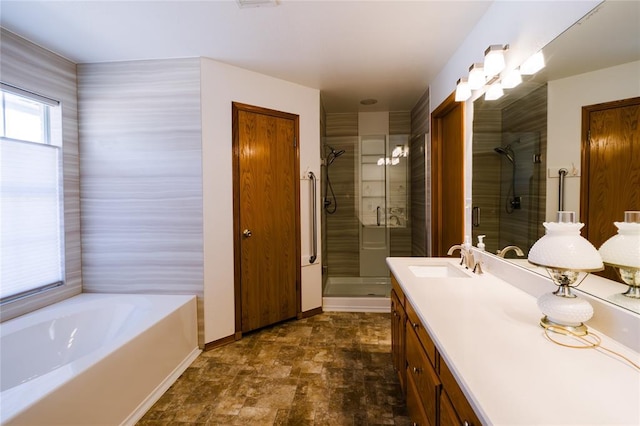 full bathroom featuring vanity, baseboards, a stall shower, stone finish flooring, and a bath