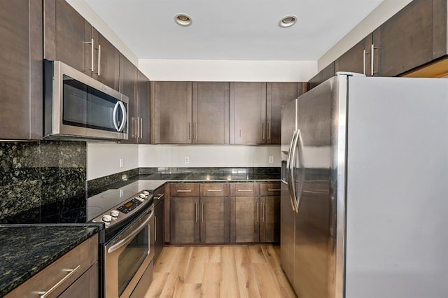 kitchen with dark brown cabinets, dark stone counters, recessed lighting, light wood-style flooring, and stainless steel appliances