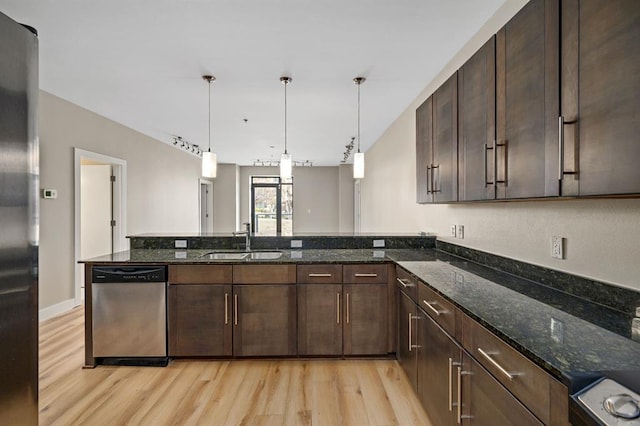 kitchen featuring a sink, dark stone counters, light wood-style floors, dark brown cabinetry, and appliances with stainless steel finishes